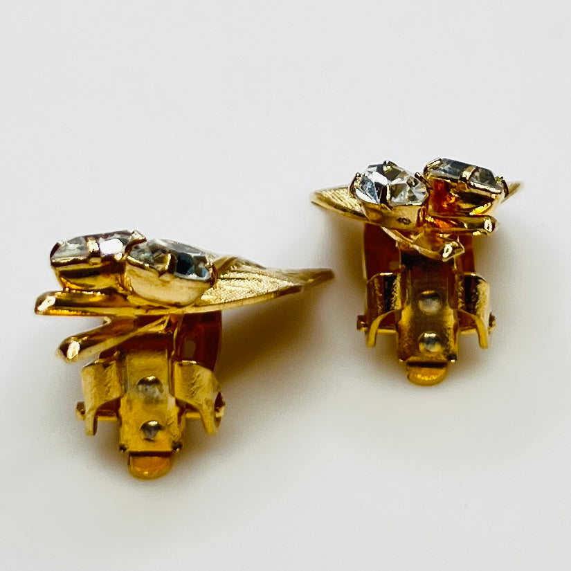 Close-up of gold-tone leaf clip-on earrings with clear rhinestones