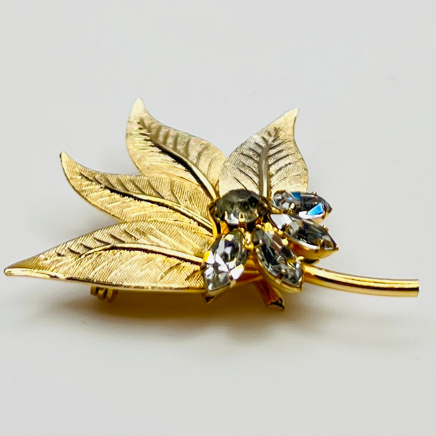 Close-up of gold-tone leaf brooch with clear rhinestones