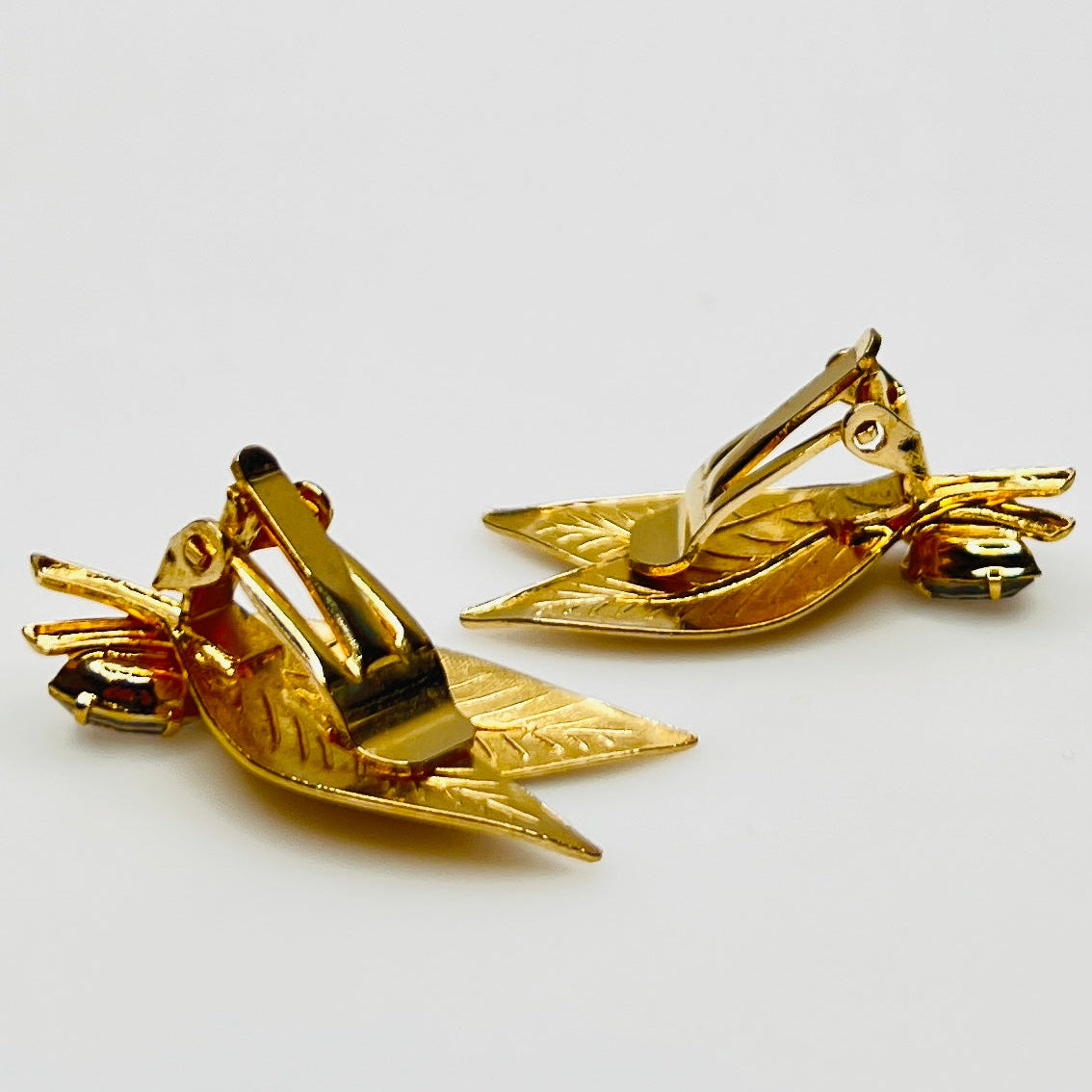 Close-up of gold-tone leaf clip-on earrings with clear rhinestones