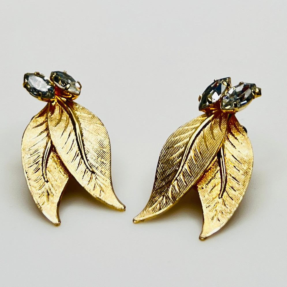 Close-up of gold-tone leaf clip-on earrings with clear rhinestones