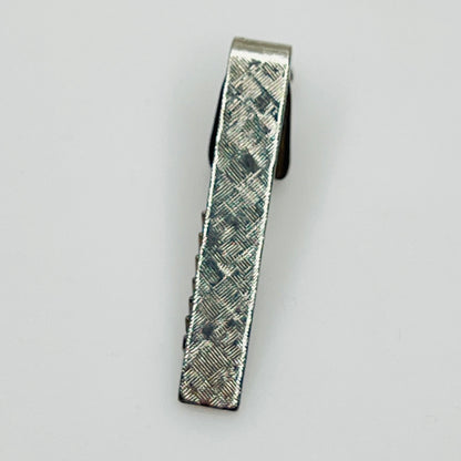 Silver textured tie clip on a light gray background