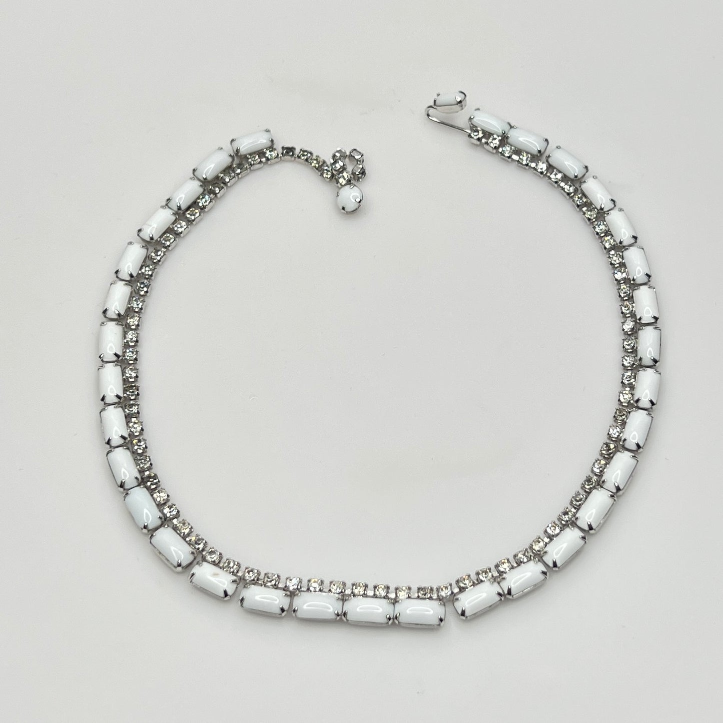 Necklace with white beads and silver accents on a light gray background