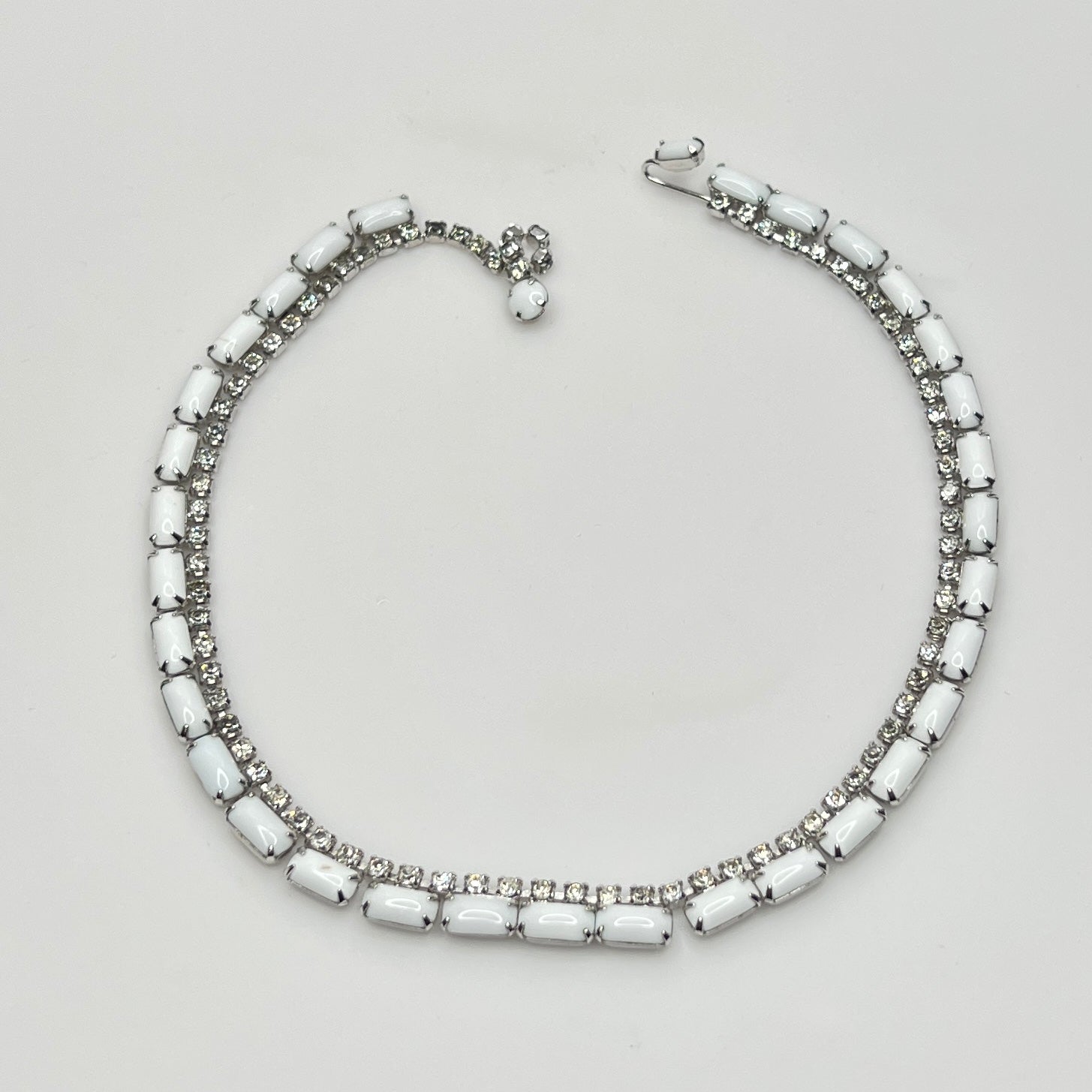 Necklace with white beads and silver accents on a light gray background