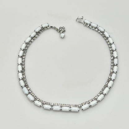 Necklace with white beads and silver accents on a light gray background