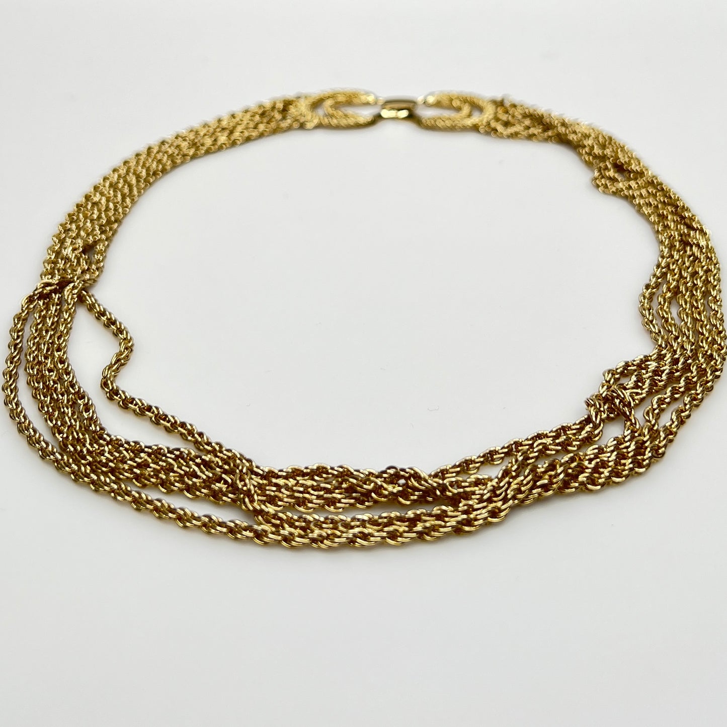 multi-strand gold tone chain necklace shown on flat surface