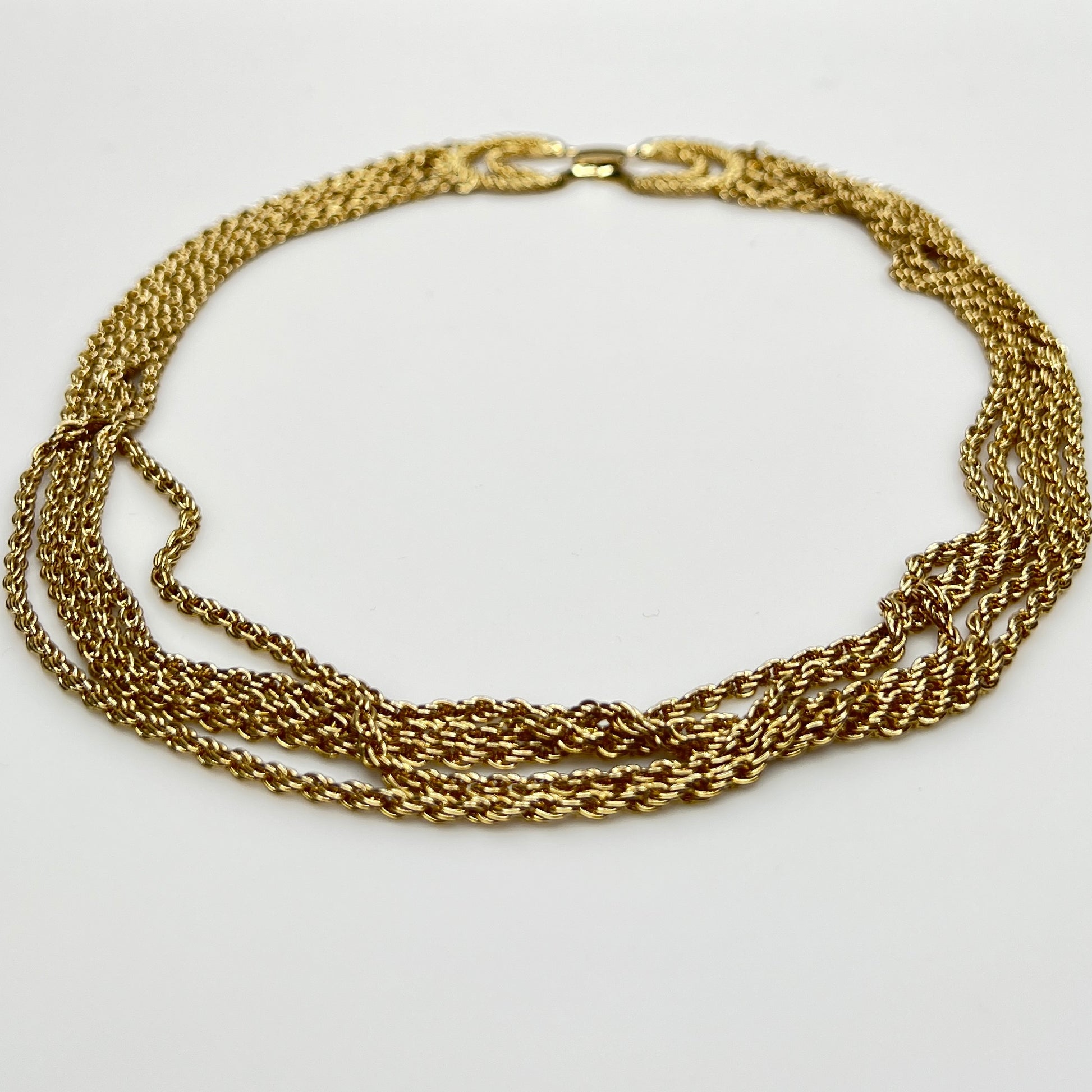 multi-strand gold tone chain necklace shown on flat surface
