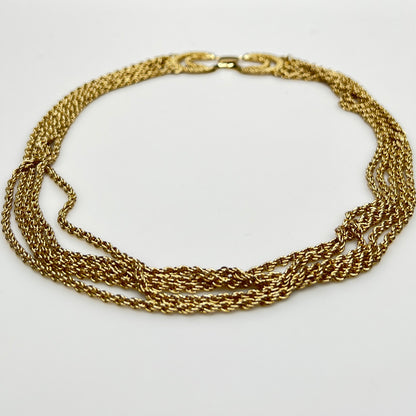 multi-strand gold tone chain necklace shown on flat surface
