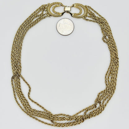 multi-strand gold tone chain necklace shown on flat surface with quarter for scale