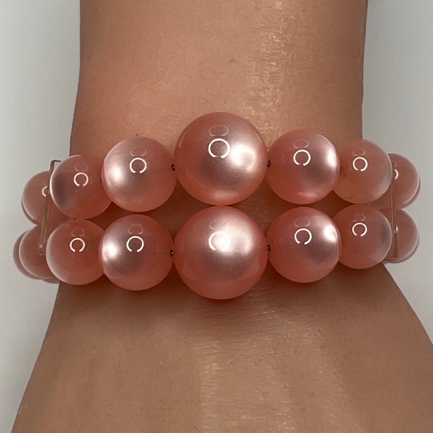 1950s pink moonglow lucite cuff bracelet on wrist, graduated round beads