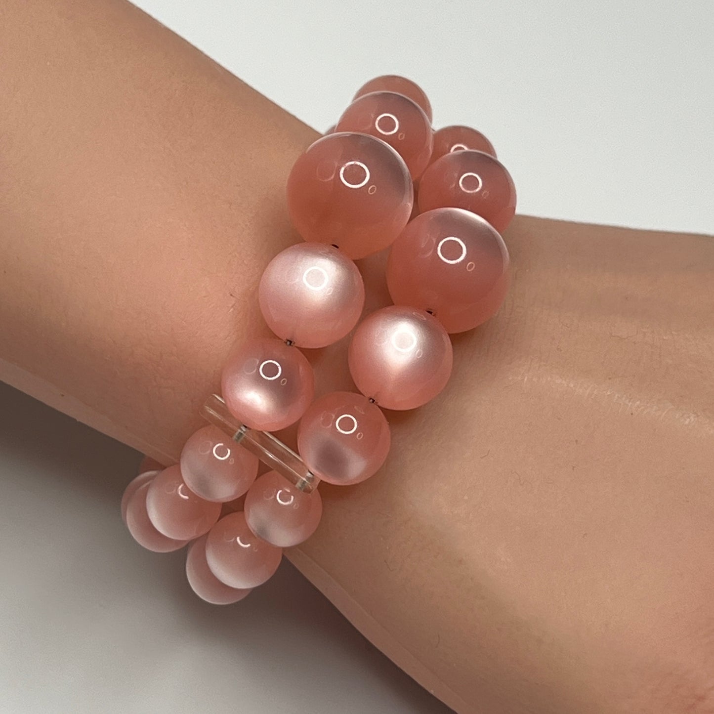 1950s pink moonglow lucite cuff bracelet on wrist, graduated round beads