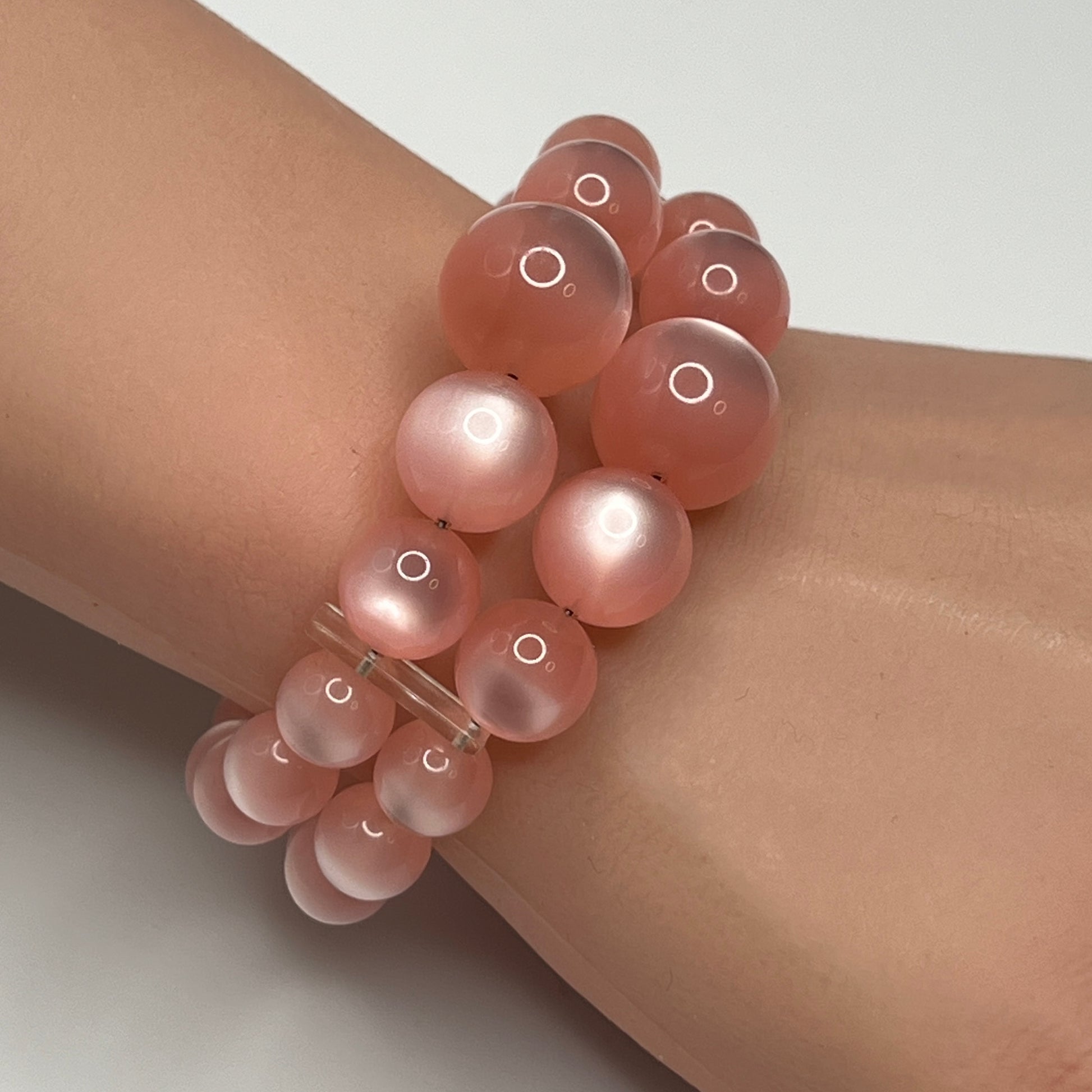 1950s pink moonglow lucite cuff bracelet on wrist, graduated round beads