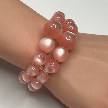 1950s pink moonglow lucite cuff bracelet on wrist, graduated round beads