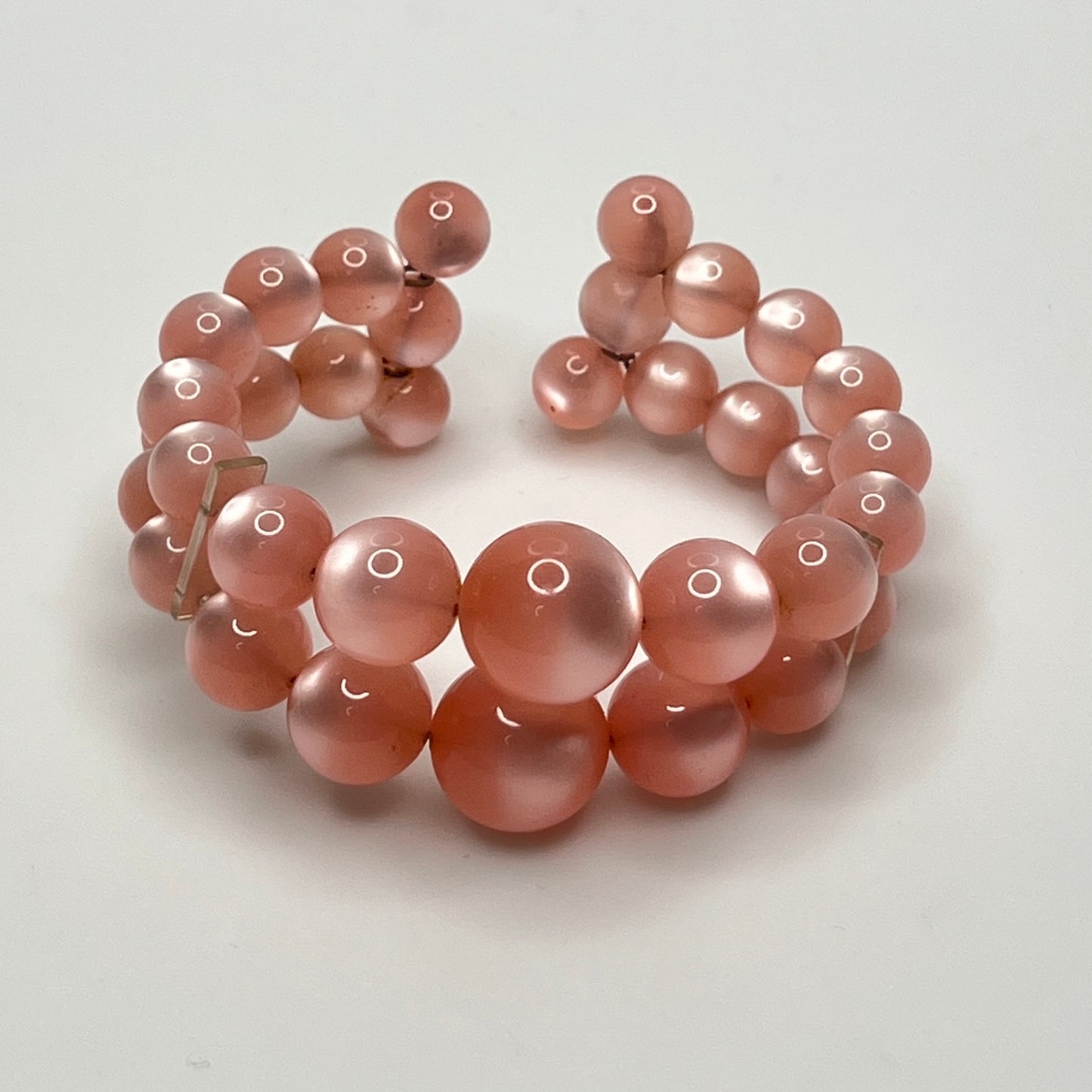 Vintage pink lucite cuff bracelet in open wire design, glowing bead detail