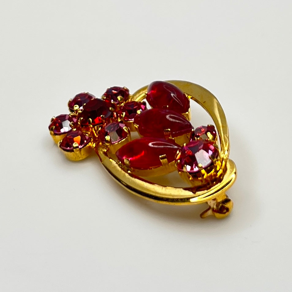 Side angle view of red rhinestone floral brooch with prong-set crystals