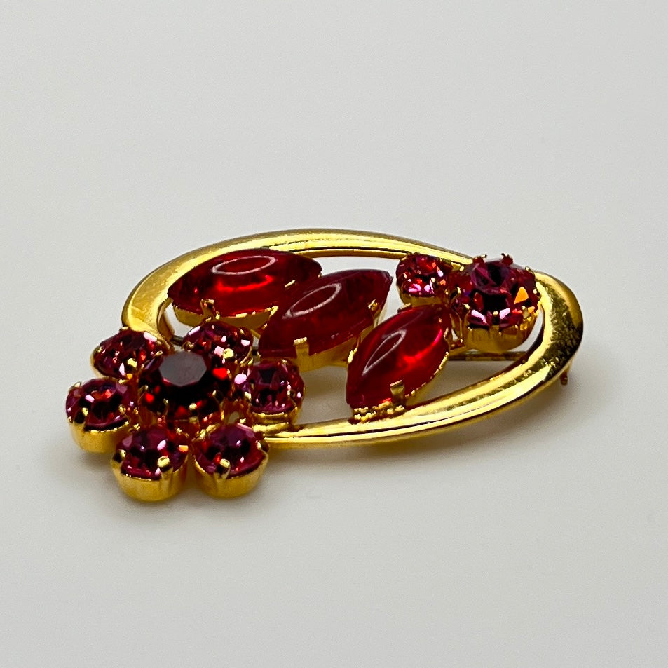 Side angle view of red rhinestone floral brooch with prong-set crystals