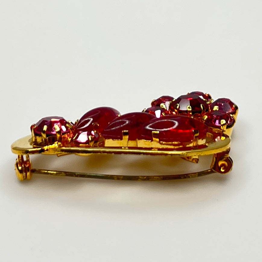 Side angle view of red rhinestone floral brooch with prong-set crystals