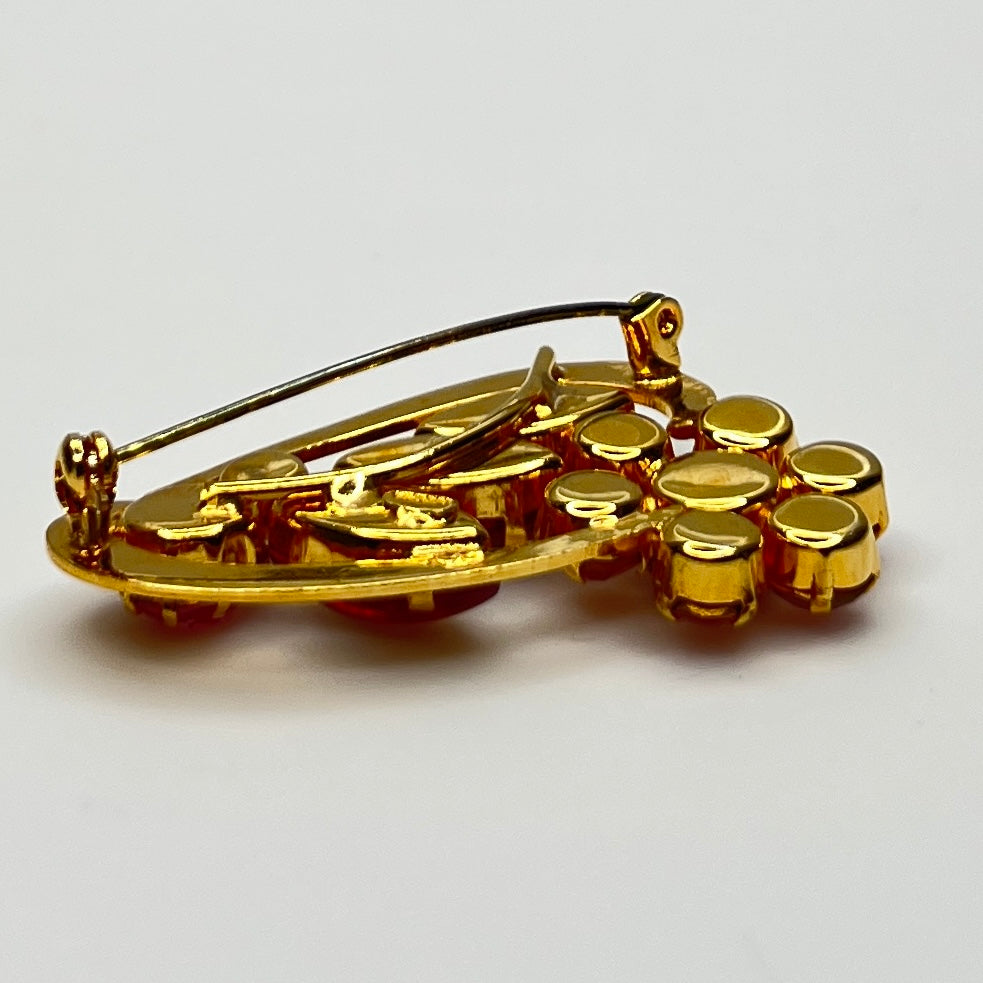 Side angle view of red rhinestone floral brooch with prong-set crystals