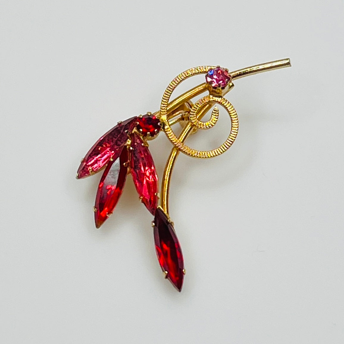 1950s pink rhinestone brooch with gold-tone spiral and navette stones