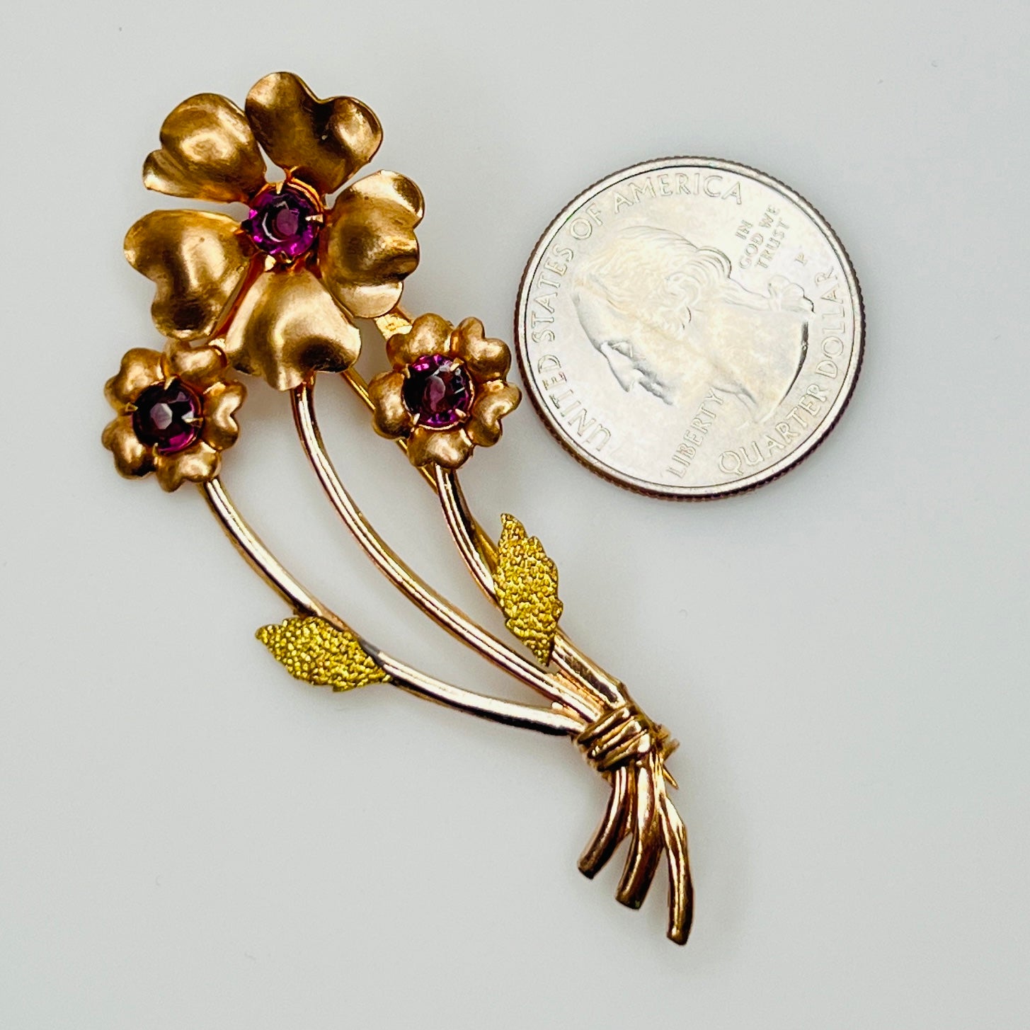 Angled view of vintage flower brooch with purple rhinestones and bouquet styling