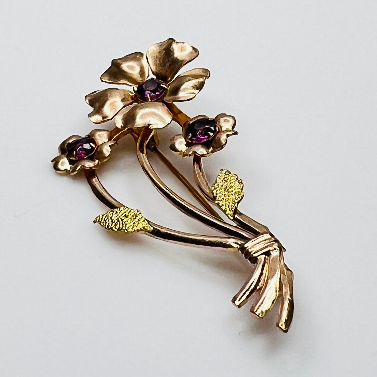 Angled view of vintage flower brooch with purple rhinestones and bouquet styling