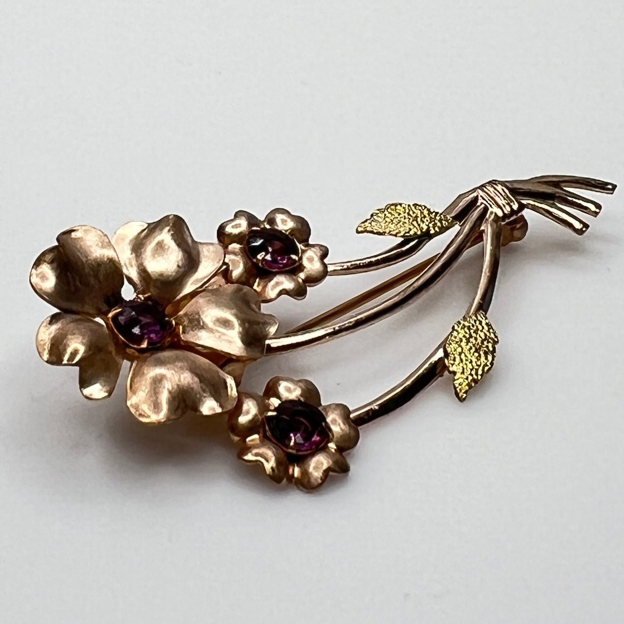 Angled view of vintage flower brooch with purple rhinestones and bouquet styling