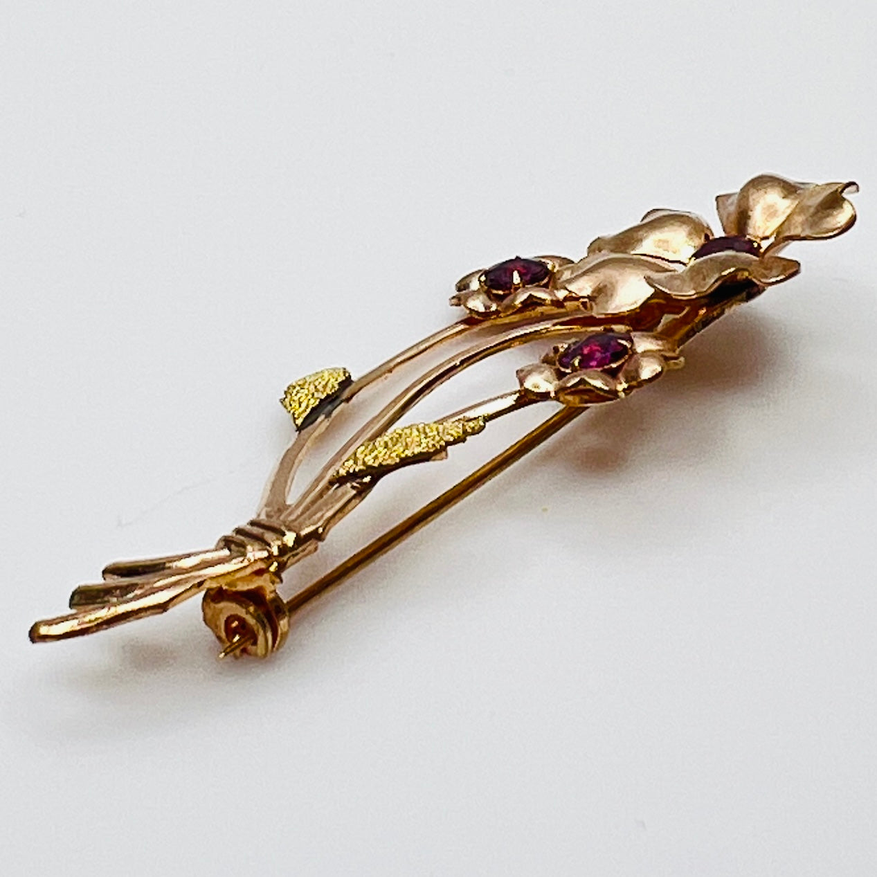 Angled view of vintage flower brooch with purple rhinestones and bouquet styling