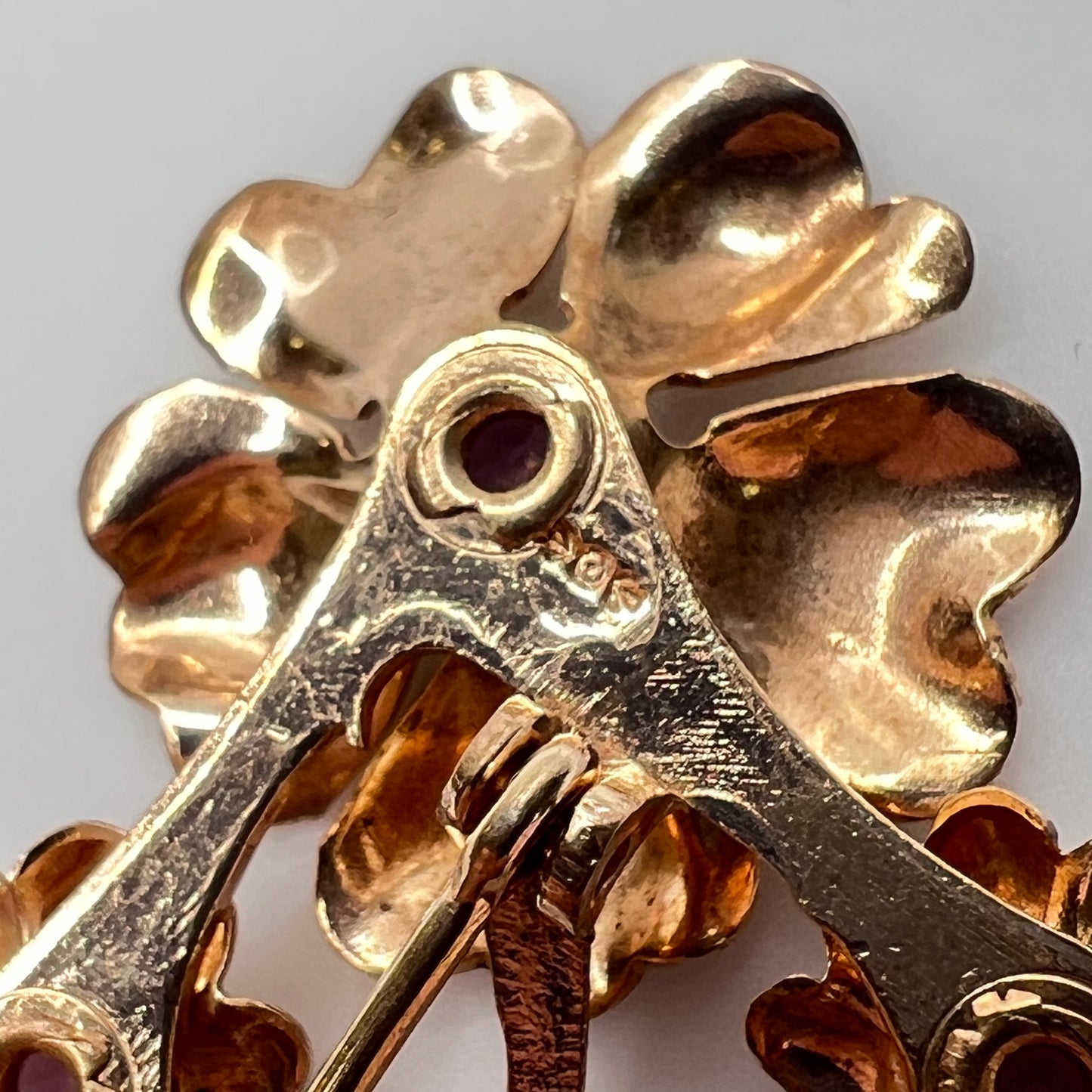Back of brooch showing partial maker’s mark with circle and arrows on gold-tone metal