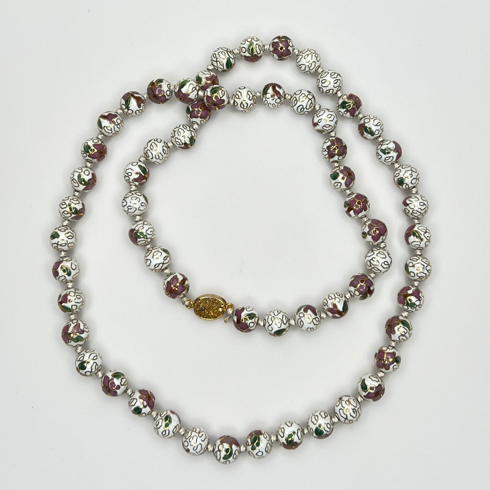 Close-up of plum and white floral enamel beads and box clasp