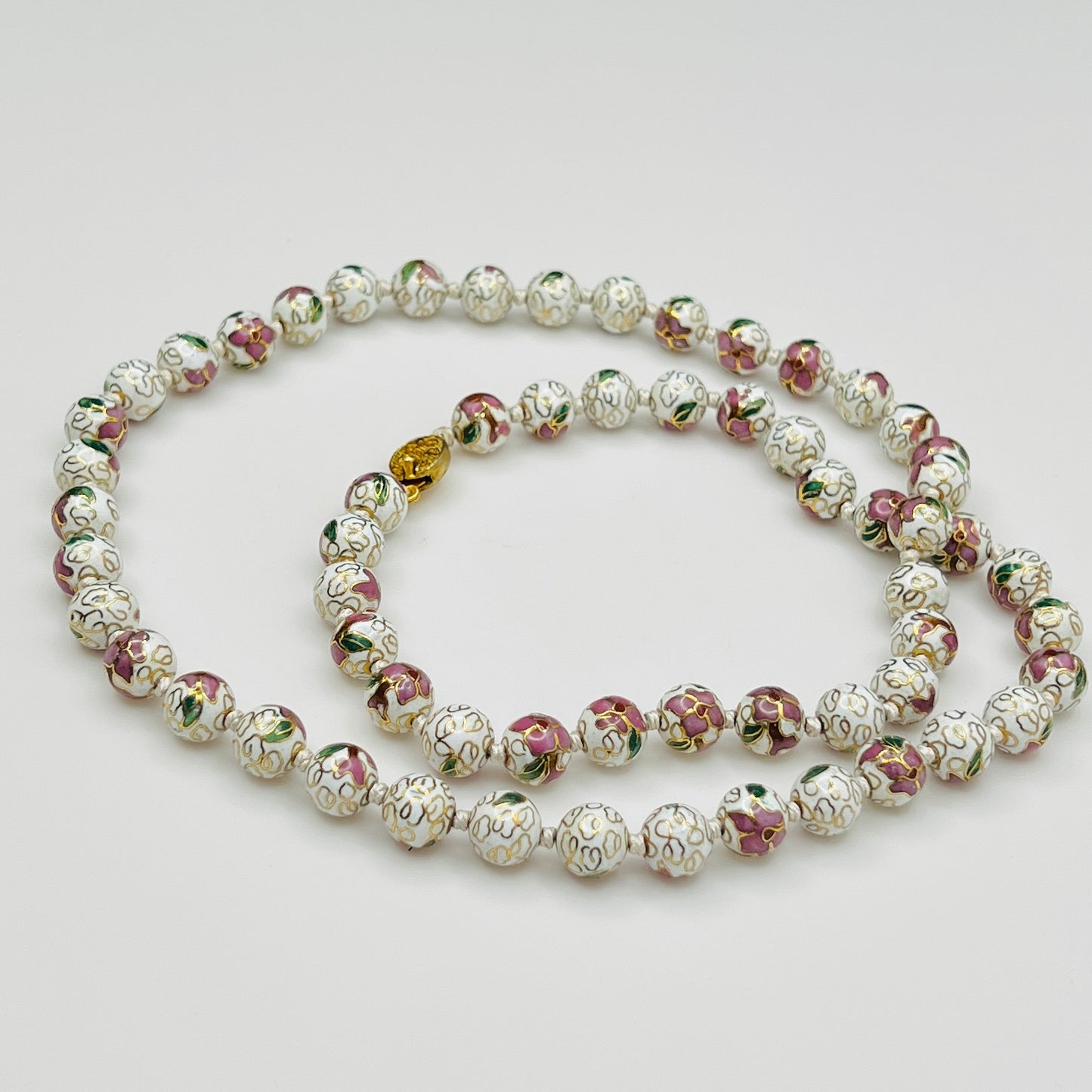 Close-up of plum and white floral enamel beads and box clasp