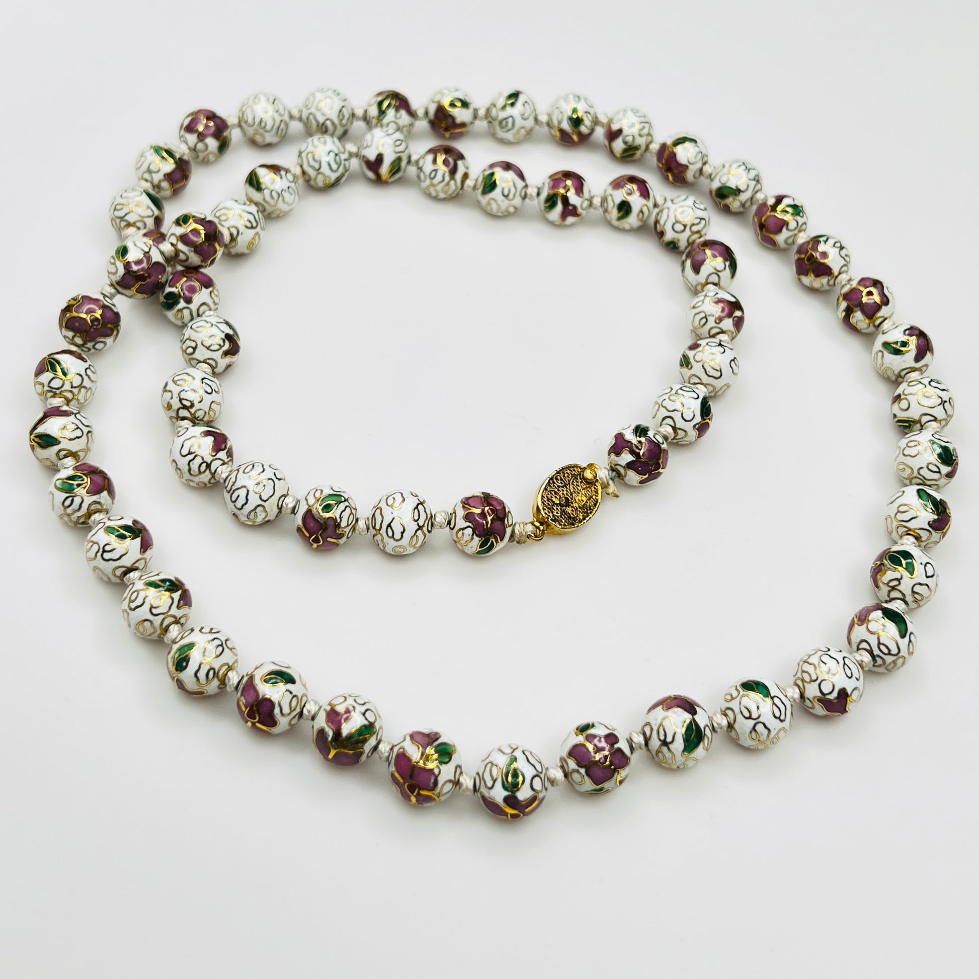 Close-up of plum and white floral enamel beads and box clasp