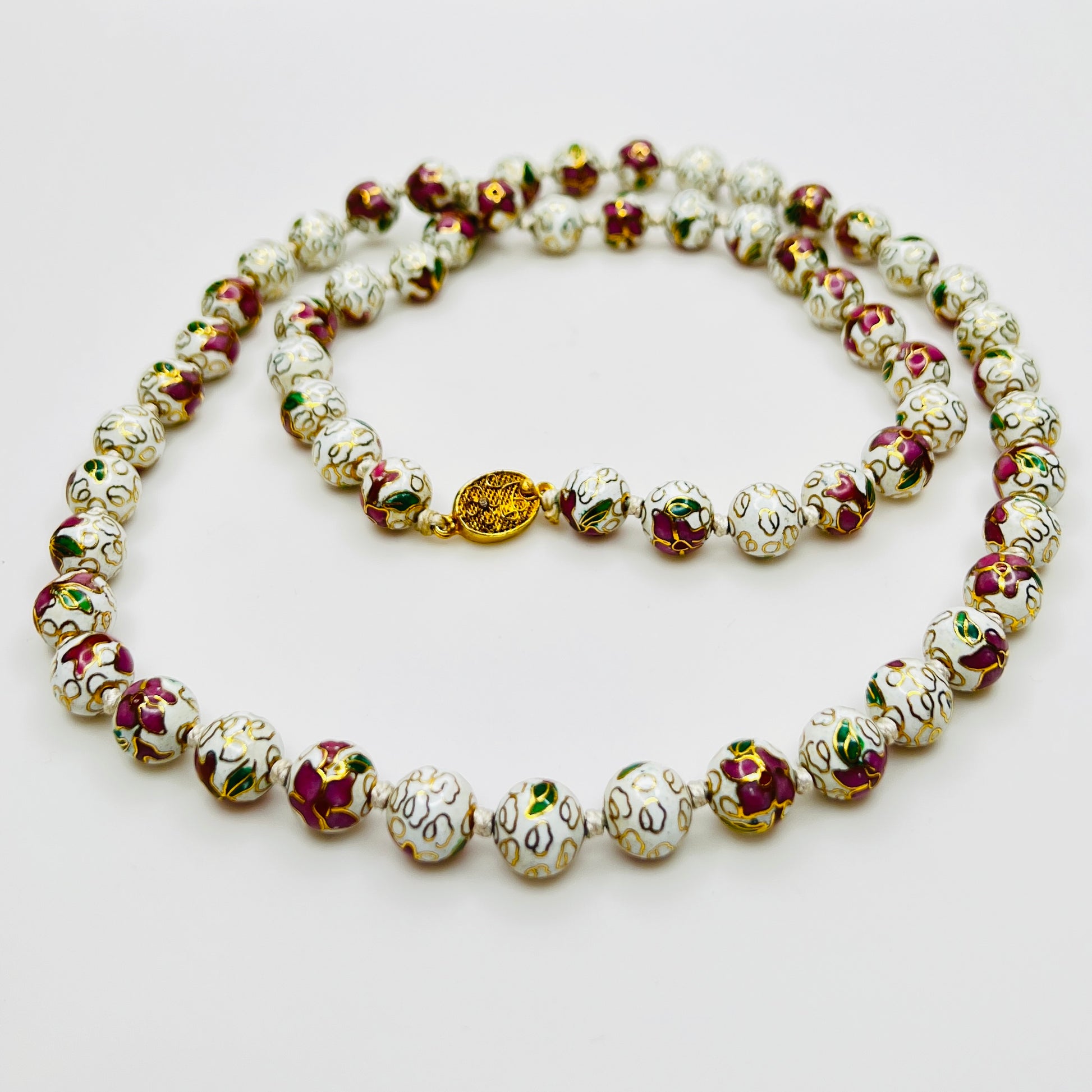 Close-up of plum and white floral enamel beads and box clasp