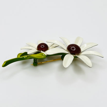 Floral brooch with white flowers and green leaves on a light gray background
