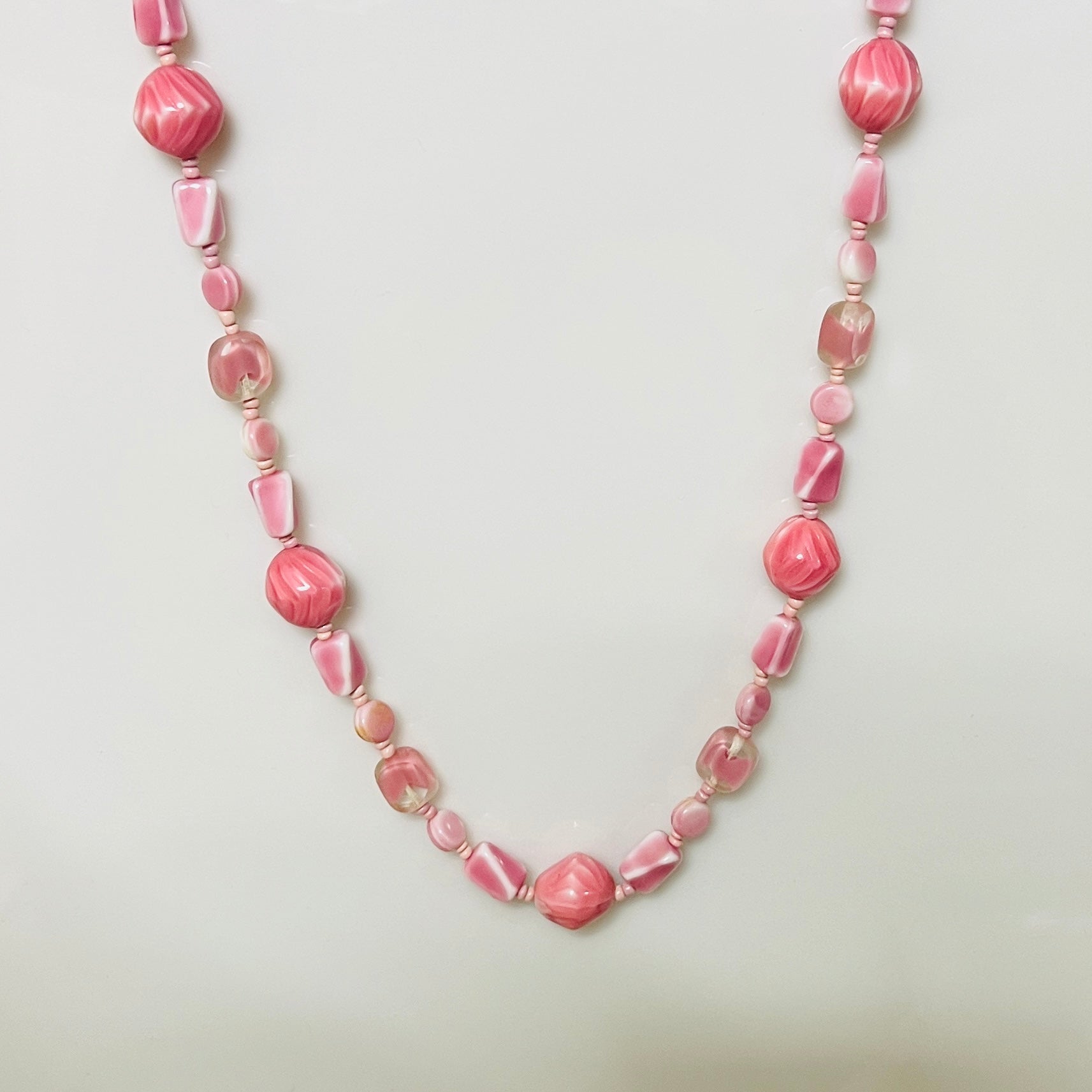 1960s pink glass bead necklace with swirled and faceted shapes in assorted pastel tones