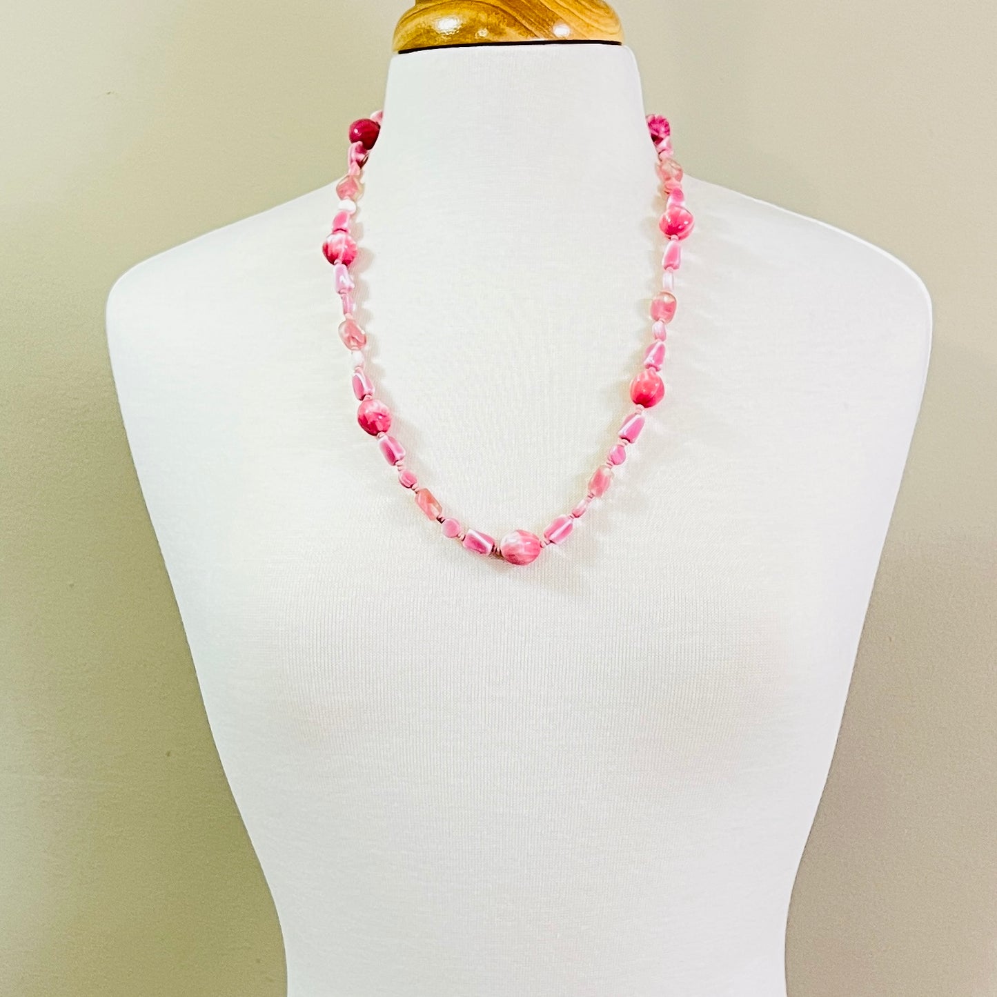 Pastel pink vintage glass necklace on mannequin, mid-length with soft mod styling