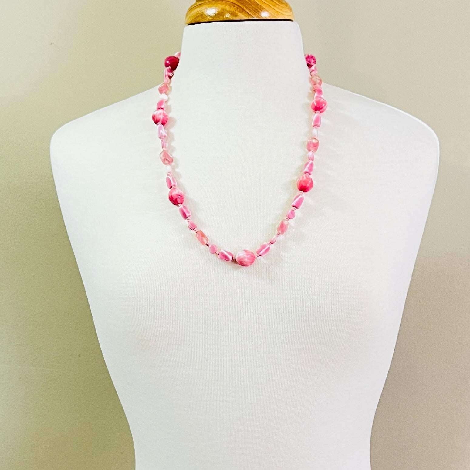 Pastel pink vintage glass necklace on mannequin, mid-length with soft mod styling