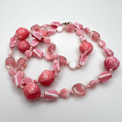 Close-up of mixed pink glass beads in various shapes and finishes with brass clasp