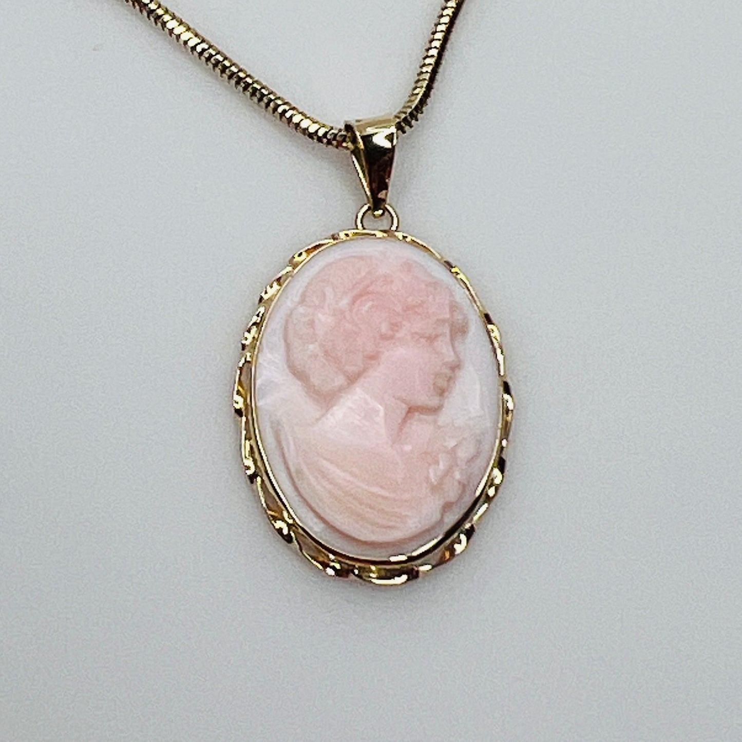 Close-up of oval pink cameo in 14K gold frame