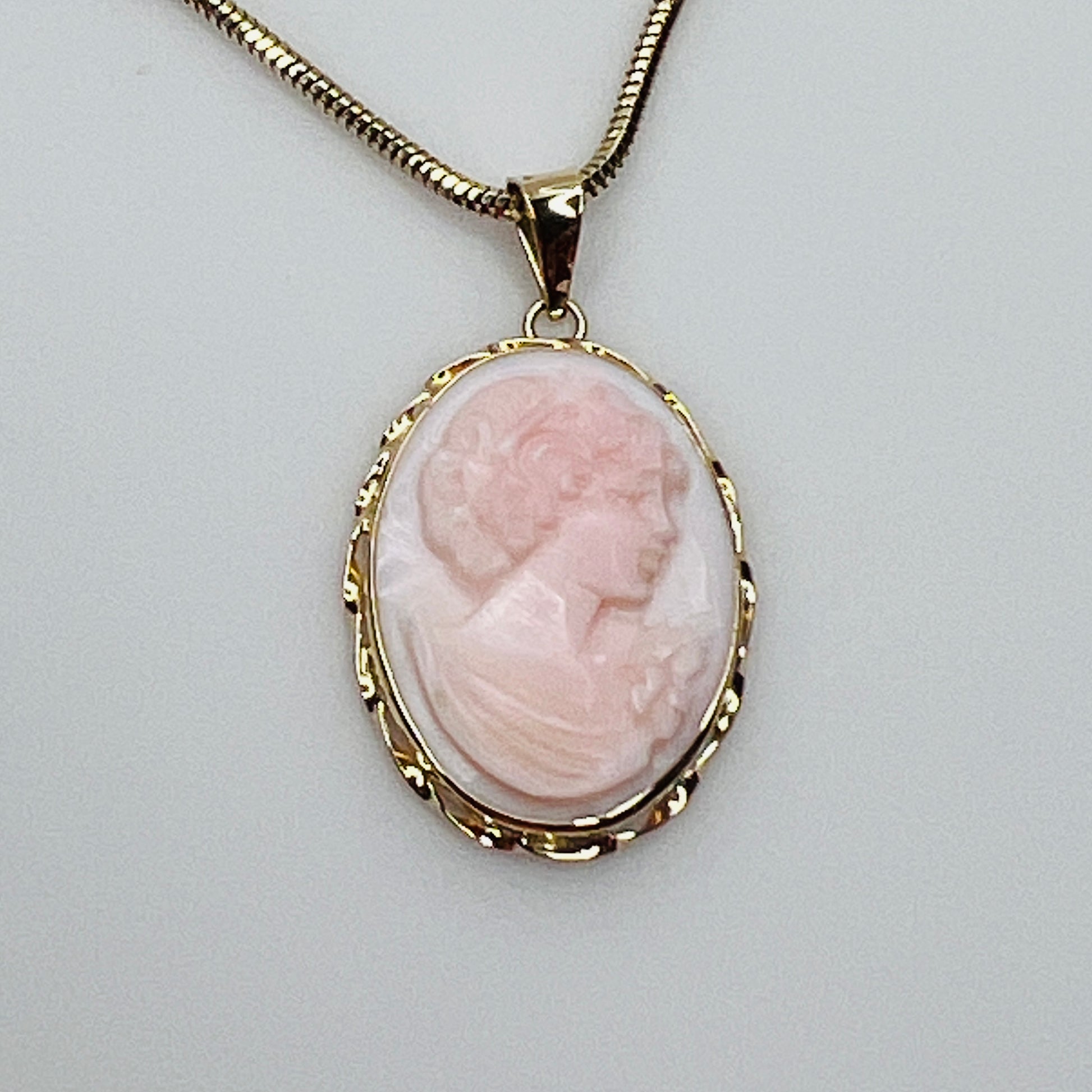 Close-up of oval pink cameo in 14K gold frame