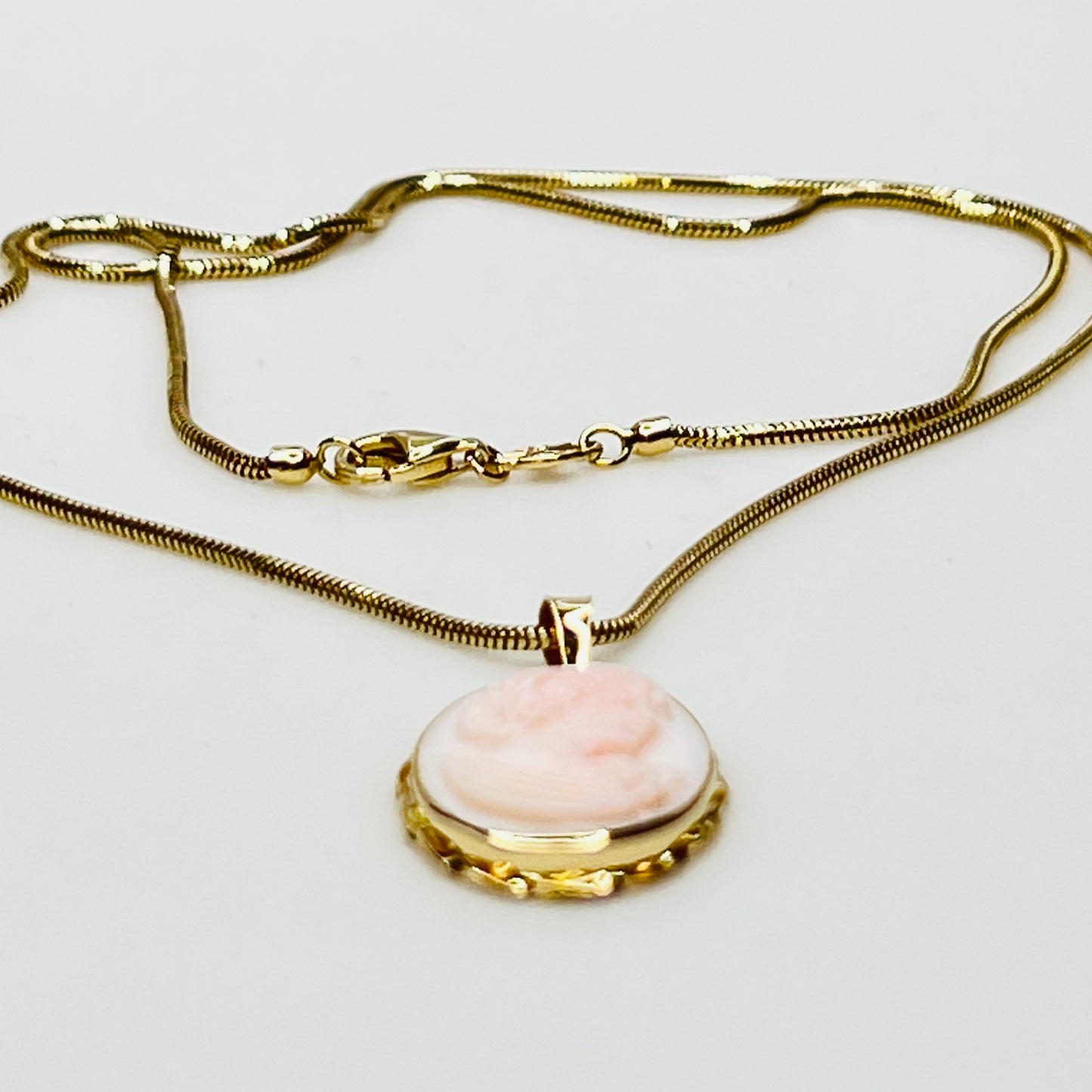 Close-up of oval pink cameo in 14K gold frame