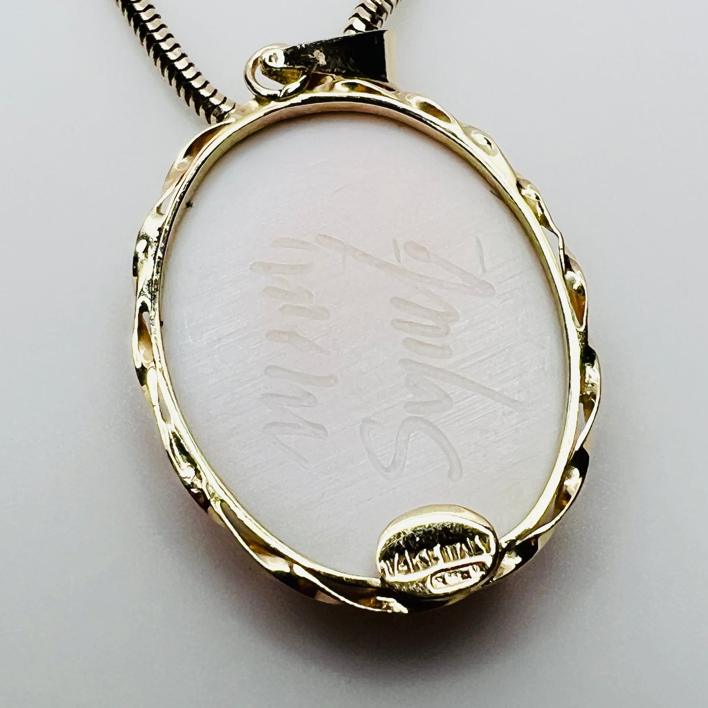 Back of cameo pendant showing artist signature and gold setting