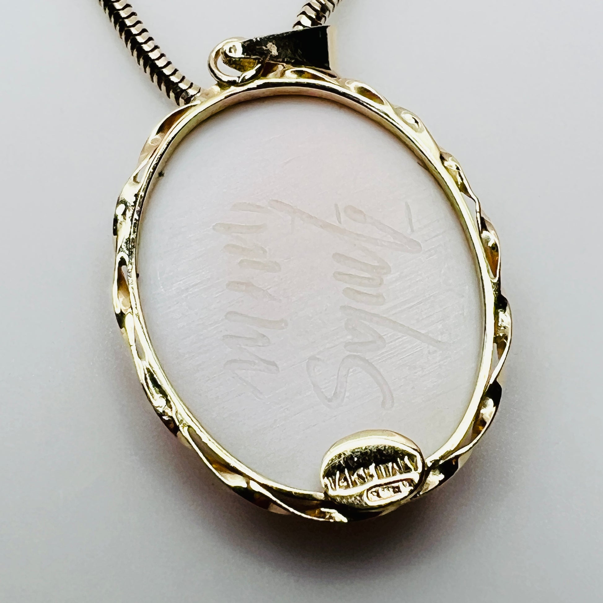 Back of cameo pendant showing artist signature and gold setting