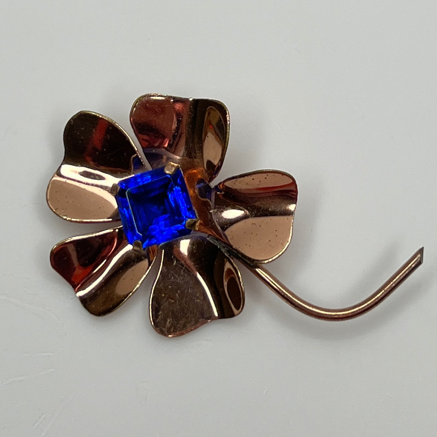 Copper-tone flower brooch with vivid cobalt blue glass rhinestone center