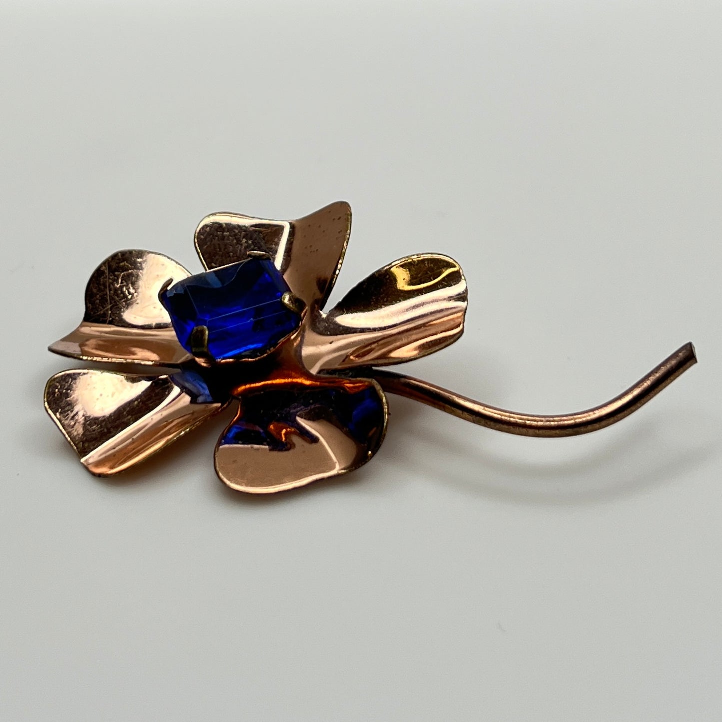 Copper-tone flower brooch with vivid cobalt blue glass rhinestone center