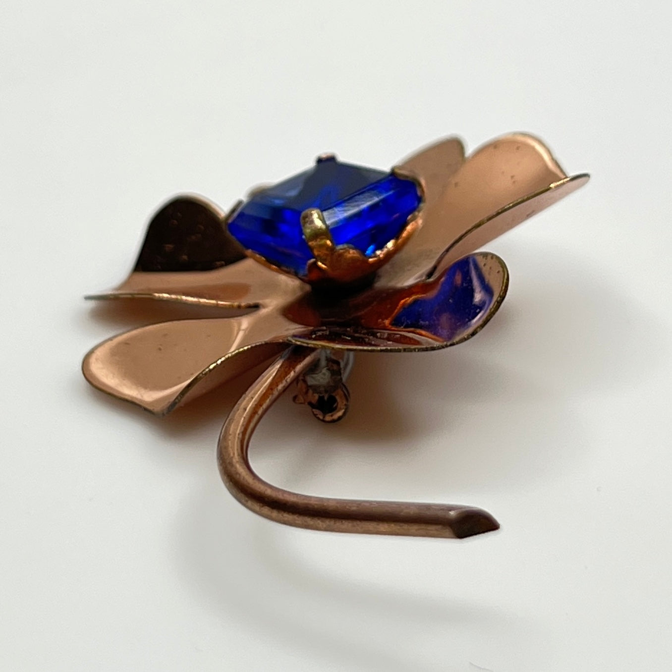 Copper-tone flower brooch with vivid cobalt blue glass rhinestone center