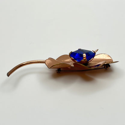 Copper-tone flower brooch with vivid cobalt blue glass rhinestone center
