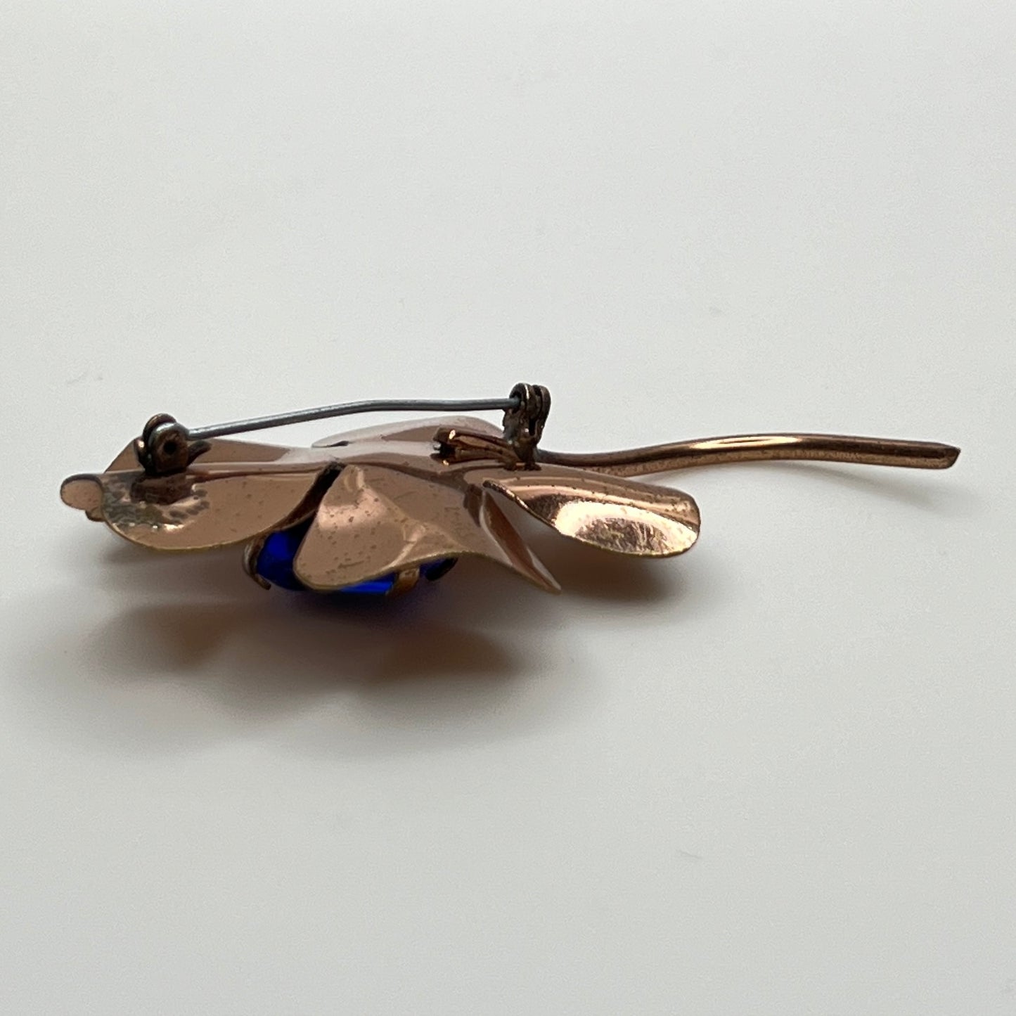 Copper-tone flower brooch with vivid cobalt blue glass rhinestone center