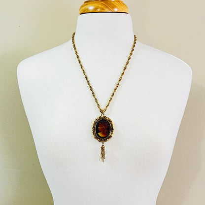 Gold tone glass cameo locket necklace with tassel drop