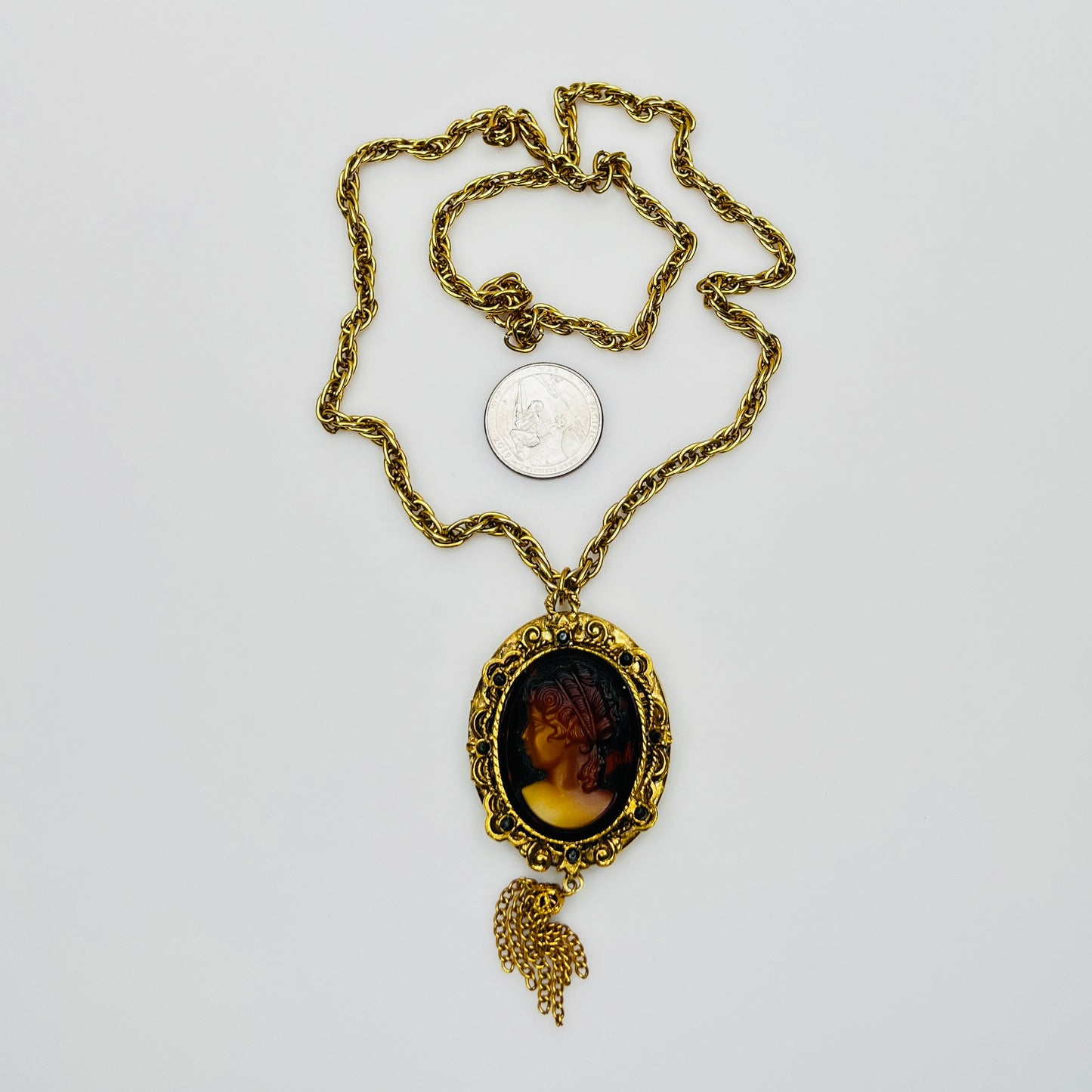 Gold tone glass cameo locket necklace with tassel drop