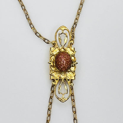 Close-up of goldstone cabochon in ornate gold tone setting