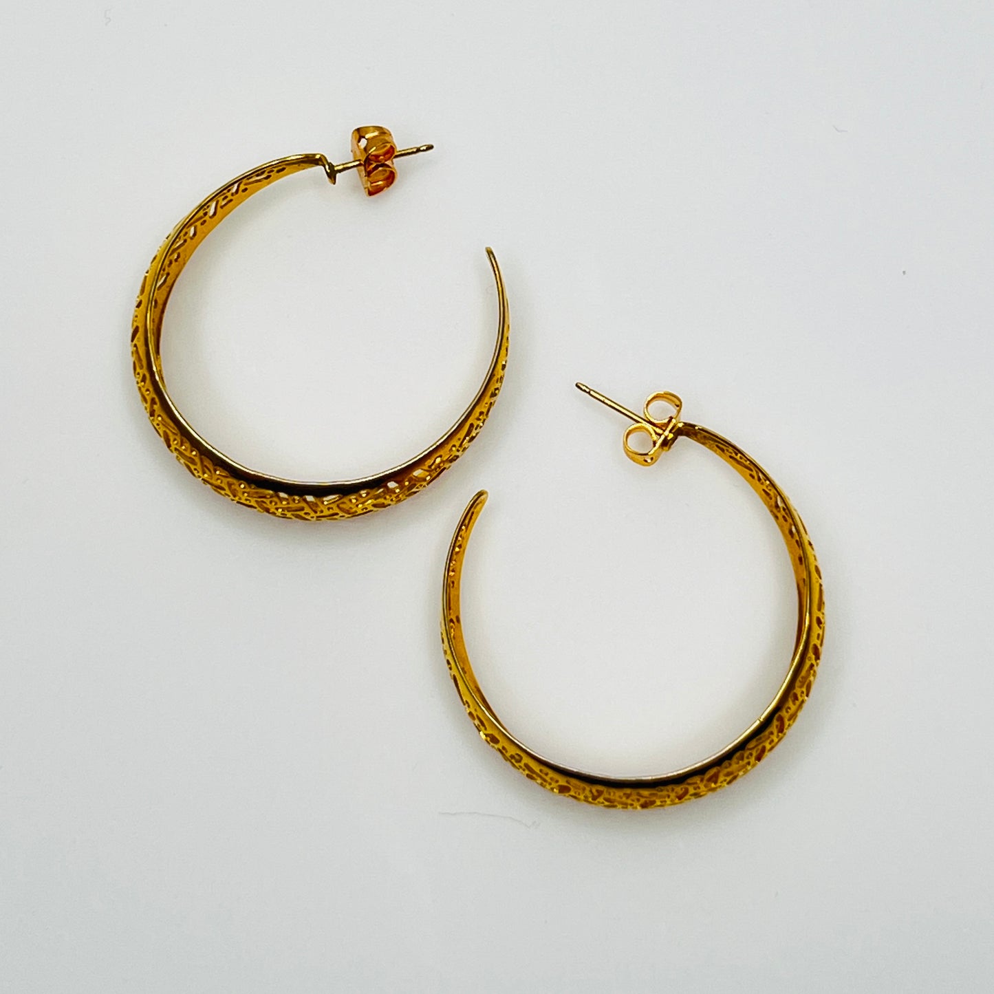 Domed gold-tone hoops with intricate lattice design, side view